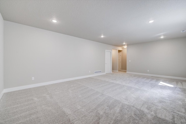 empty room with a textured ceiling and light colored carpet