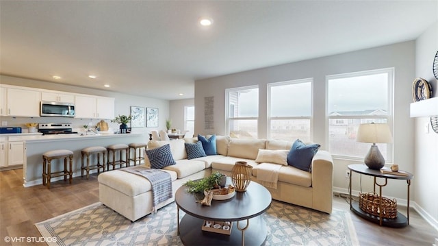 living area featuring baseboards, recessed lighting, and light wood-style floors