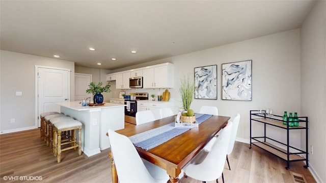 dining space featuring baseboards, light wood-style flooring, visible vents, and recessed lighting