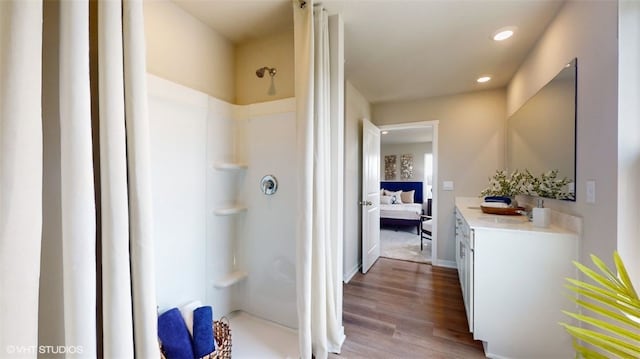 bathroom with recessed lighting, wood finished floors, vanity, a stall shower, and ensuite bath