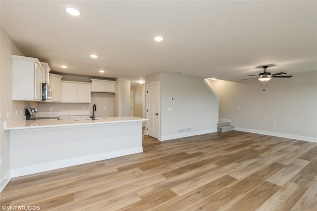 kitchen with stainless steel appliances, sink, white cabinets, light hardwood / wood-style floors, and ceiling fan