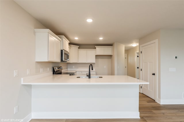 kitchen with white cabinetry, appliances with stainless steel finishes, sink, and light wood-type flooring