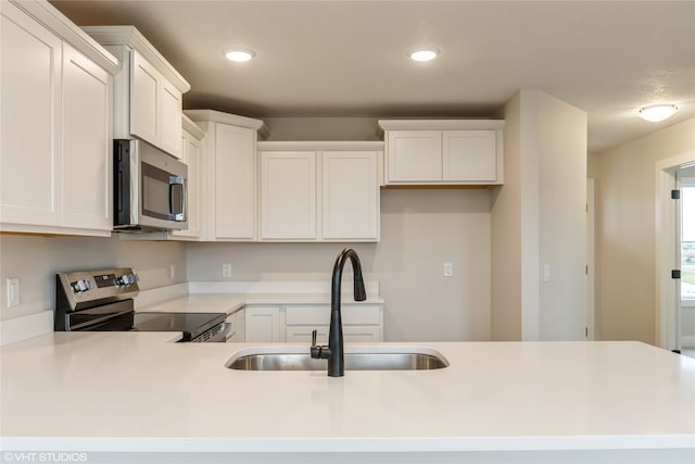 kitchen with appliances with stainless steel finishes, white cabinetry, and sink