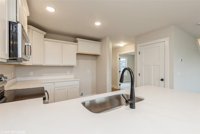 kitchen featuring range, sink, and white cabinets