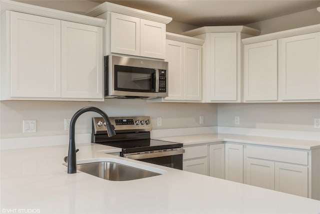 kitchen with appliances with stainless steel finishes, white cabinets, and sink