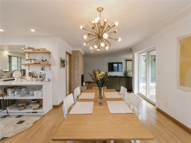 dining space featuring light hardwood / wood-style flooring, a notable chandelier, and a brick fireplace