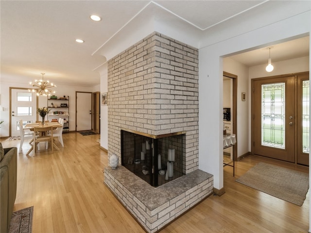 living room featuring hardwood / wood-style flooring, an inviting chandelier, and a brick fireplace