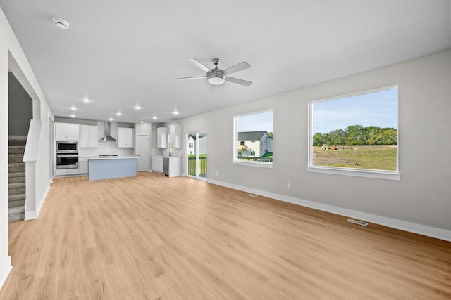 unfurnished living room featuring ceiling fan and light hardwood / wood-style flooring