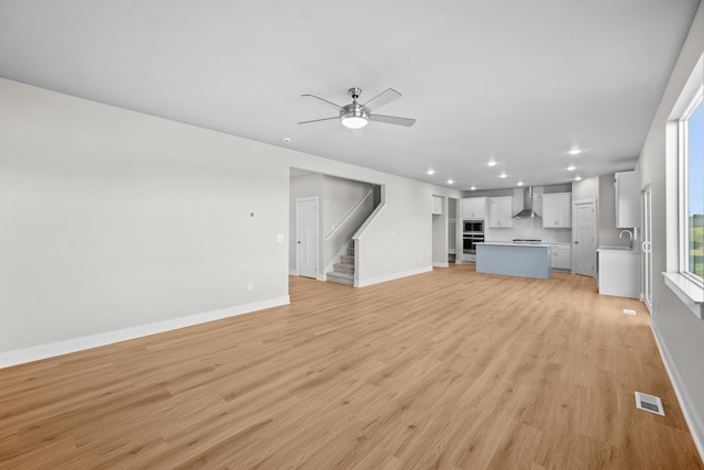 unfurnished living room featuring ceiling fan, sink, and light hardwood / wood-style floors