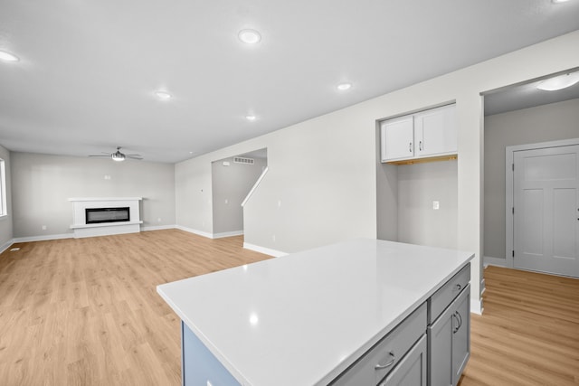 kitchen with a center island, white cabinets, ceiling fan, gray cabinets, and light hardwood / wood-style floors