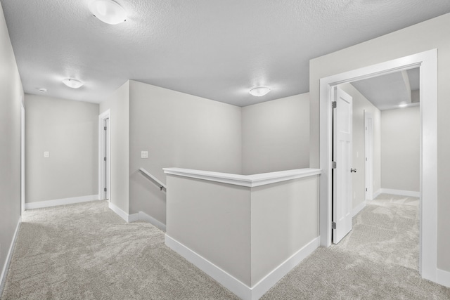 hallway featuring light carpet and a textured ceiling