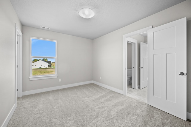 spare room with a textured ceiling and light colored carpet