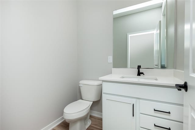 bathroom with hardwood / wood-style floors, vanity with extensive cabinet space, and toilet