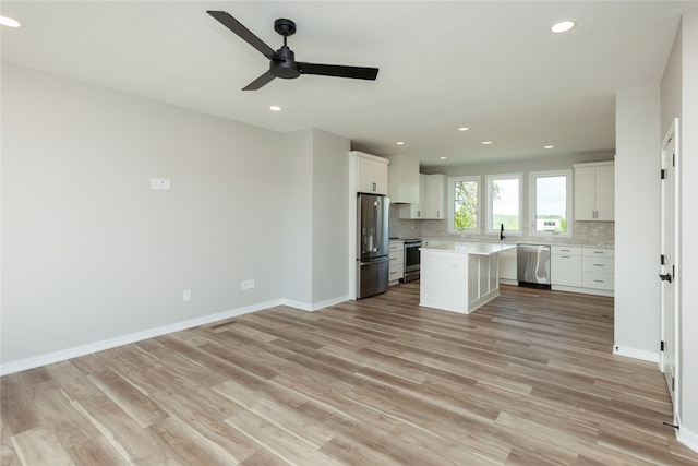 kitchen with white cabinets, light hardwood / wood-style floors, appliances with stainless steel finishes, and a center island