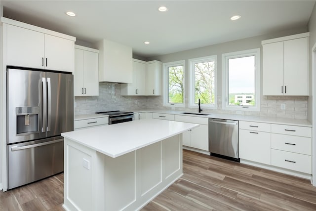 kitchen with a center island, light wood-type flooring, white cabinetry, backsplash, and appliances with stainless steel finishes