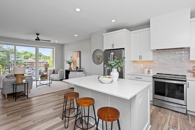 2738 Fleur Dr Unit 23, Des Moines, IA 50321 - kitchen featuring stainless steel appliances, open floor plan, a breakfast bar, light wood-type flooring, and recessed lighting