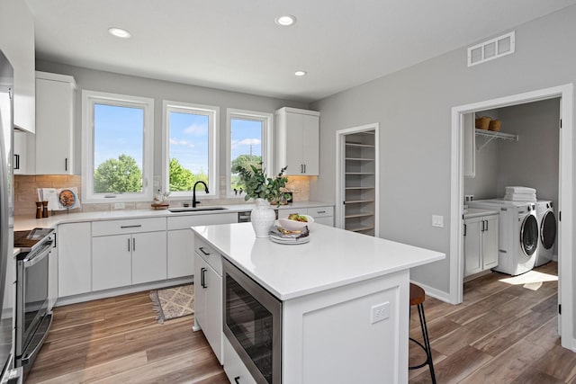 2738 Fleur Dr Unit 23, Des Moines, IA 50321 - kitchen featuring washer and clothes dryer, a sink, appliances with stainless steel finishes, backsplash, and recessed lighting