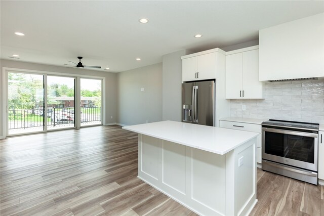 kitchen with a center island, white cabinets, light hardwood / wood-style floors, backsplash, and stainless steel appliances