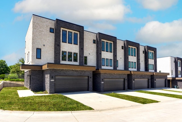 2724 Fleur Dr Unit 16, Des Moines, IA 50321 - view of front facade with an attached garage, concrete driveway, brick siding, and a front lawn