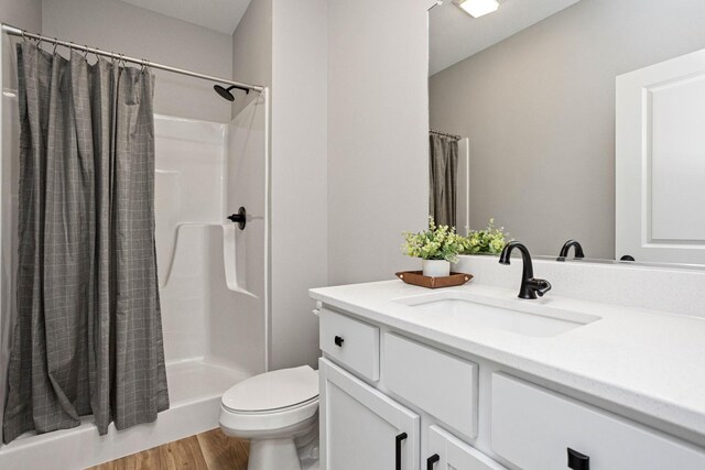 2720 Fleur Dr Unit 14, Des Moines, IA 50321 - bathroom featuring toilet, a shower with curtain, wood finished floors, and vanity