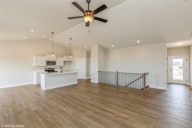 unfurnished living room featuring light hardwood / wood-style floors, vaulted ceiling, and ceiling fan