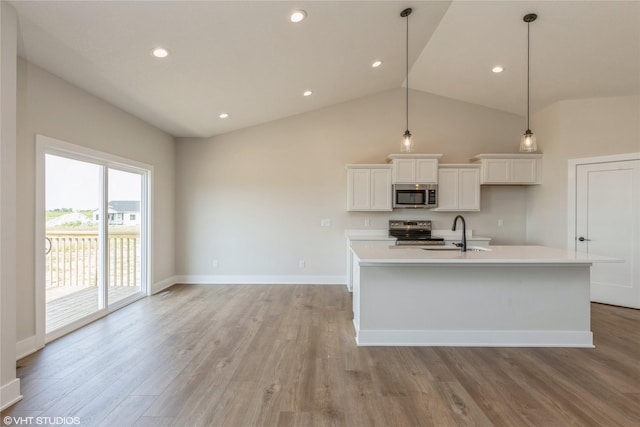 kitchen featuring lofted ceiling, a kitchen island with sink, sink, light hardwood / wood-style floors, and stainless steel appliances