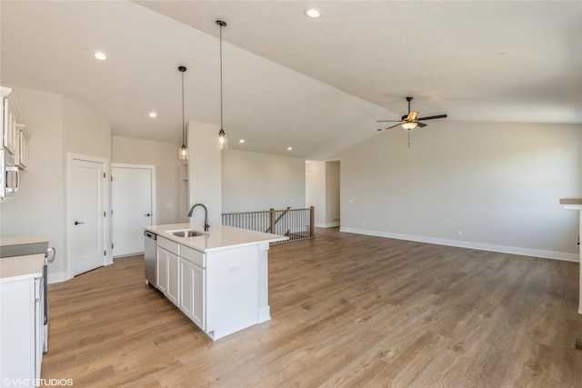 kitchen with sink, stainless steel appliances, pendant lighting, vaulted ceiling, and a kitchen island with sink