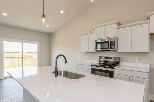 kitchen with appliances with stainless steel finishes, light wood-type flooring, light stone counters, sink, and hanging light fixtures