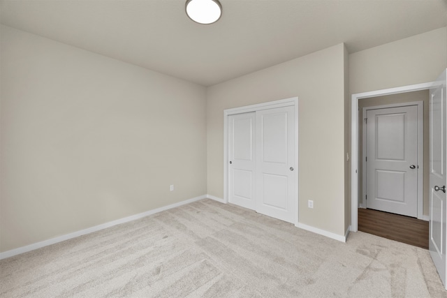 unfurnished bedroom with light colored carpet and a closet