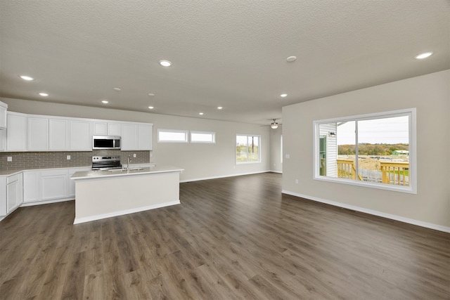 kitchen featuring appliances with stainless steel finishes, white cabinetry, a healthy amount of sunlight, and dark wood-type flooring