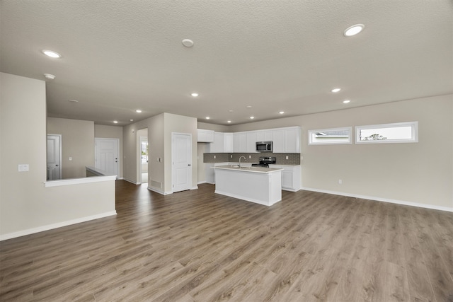 unfurnished living room with sink, a textured ceiling, and light hardwood / wood-style floors