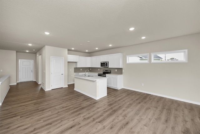 kitchen with sink, light wood-type flooring, stainless steel appliances, white cabinets, and a kitchen island with sink