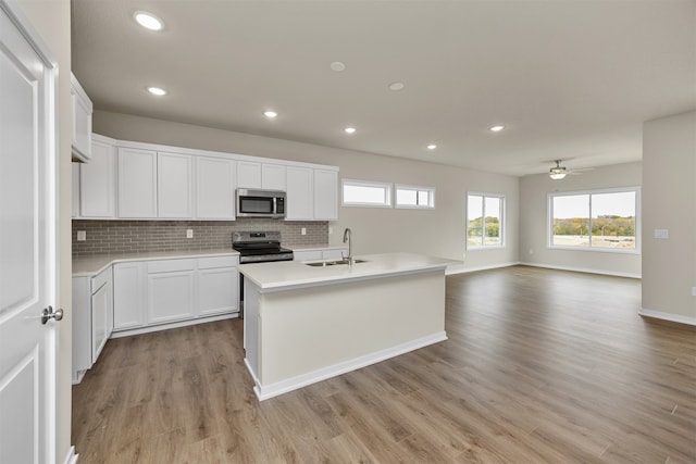 kitchen featuring white cabinets, a kitchen island with sink, sink, light hardwood / wood-style floors, and stainless steel appliances