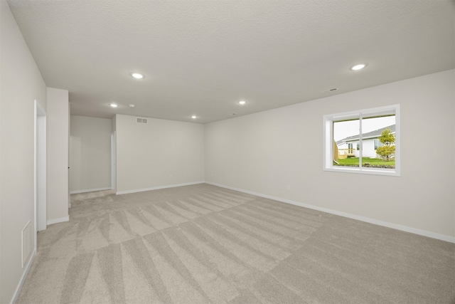 spare room featuring a textured ceiling and light colored carpet