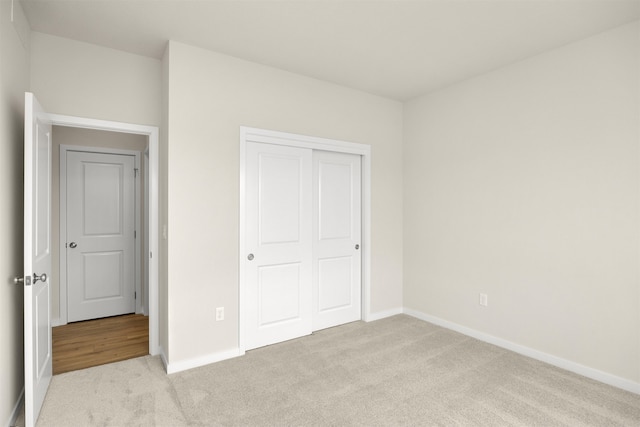 unfurnished bedroom featuring light carpet and a closet