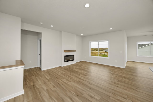 unfurnished living room with ceiling fan and light wood-type flooring