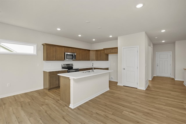 kitchen featuring light hardwood / wood-style floors, a kitchen island with sink, stainless steel appliances, and sink