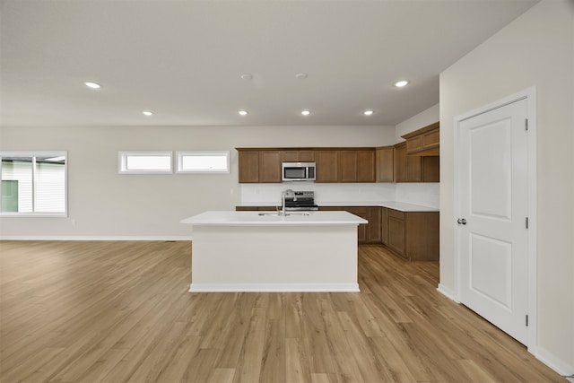 kitchen with a center island with sink, sink, light hardwood / wood-style flooring, and stainless steel appliances