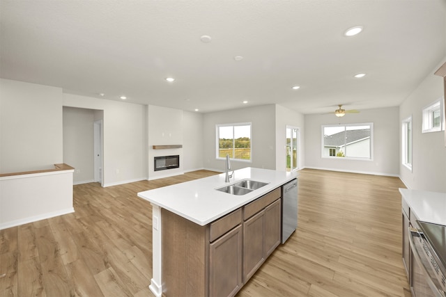 kitchen with light hardwood / wood-style flooring, stainless steel appliances, sink, and a center island with sink