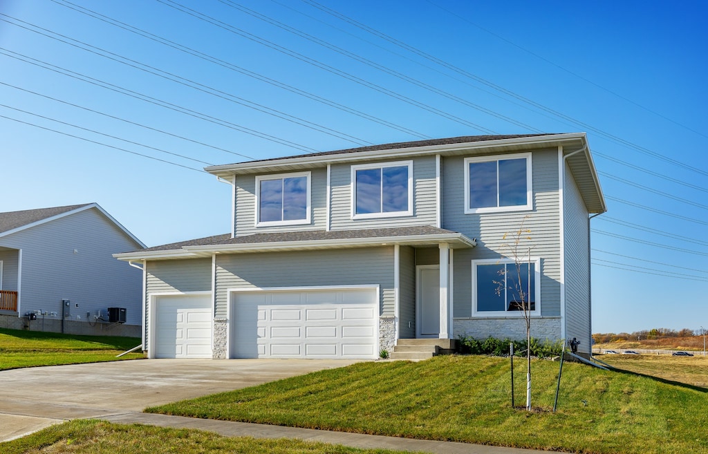 view of front of home with a garage, a front lawn, and central AC unit