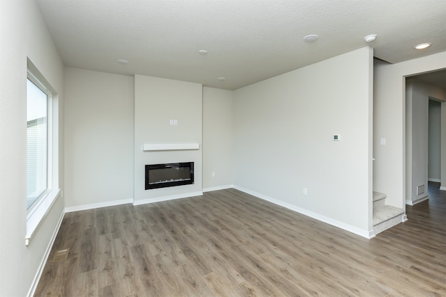 unfurnished living room featuring a textured ceiling and light wood-type flooring