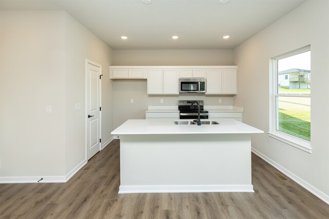 kitchen featuring a center island with sink, appliances with stainless steel finishes, white cabinetry, and a healthy amount of sunlight