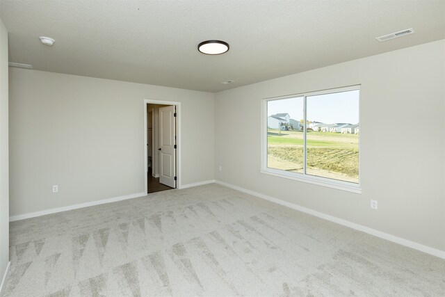 empty room with light carpet and a textured ceiling