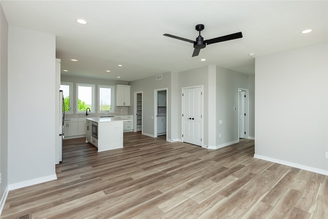 kitchen with white cabinets, light hardwood / wood-style flooring, ceiling fan, and a center island