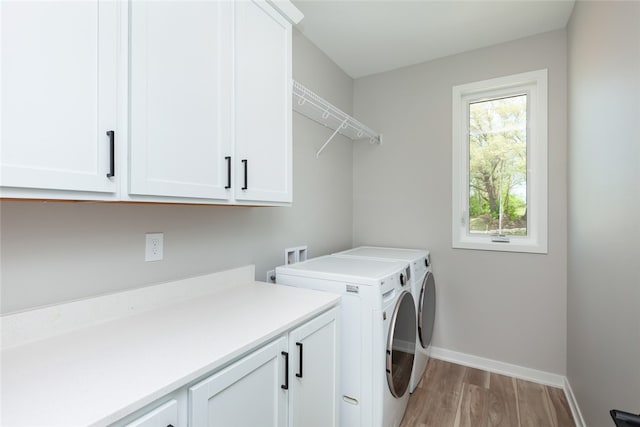 clothes washing area featuring cabinets, washer hookup, light hardwood / wood-style floors, and washer and dryer