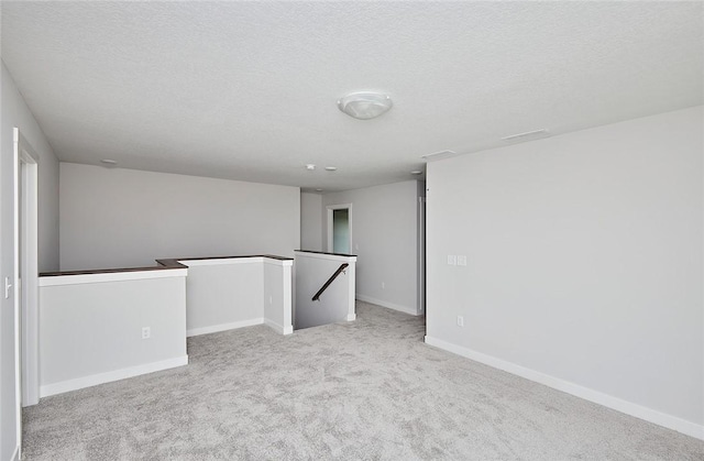 unfurnished room featuring carpet, baseboards, and a textured ceiling