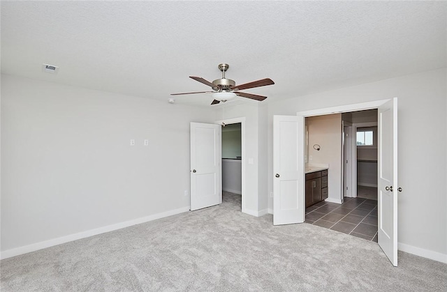 unfurnished bedroom featuring baseboards, visible vents, carpet, a spacious closet, and a textured ceiling