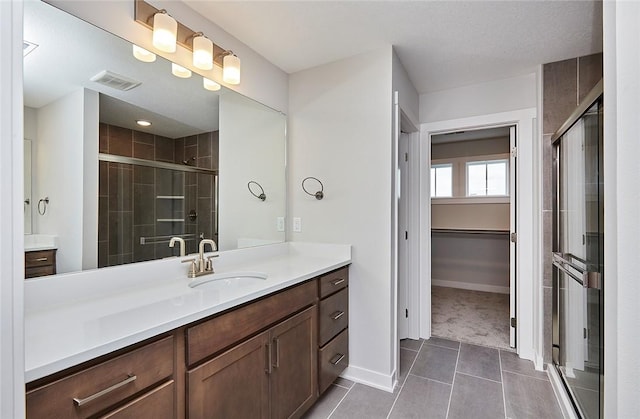 full bathroom with a stall shower, visible vents, a walk in closet, and vanity