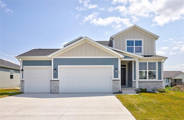 craftsman house featuring a garage, concrete driveway, stone siding, board and batten siding, and a front yard