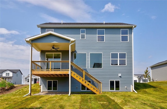 back of property with a ceiling fan, a yard, and stairway